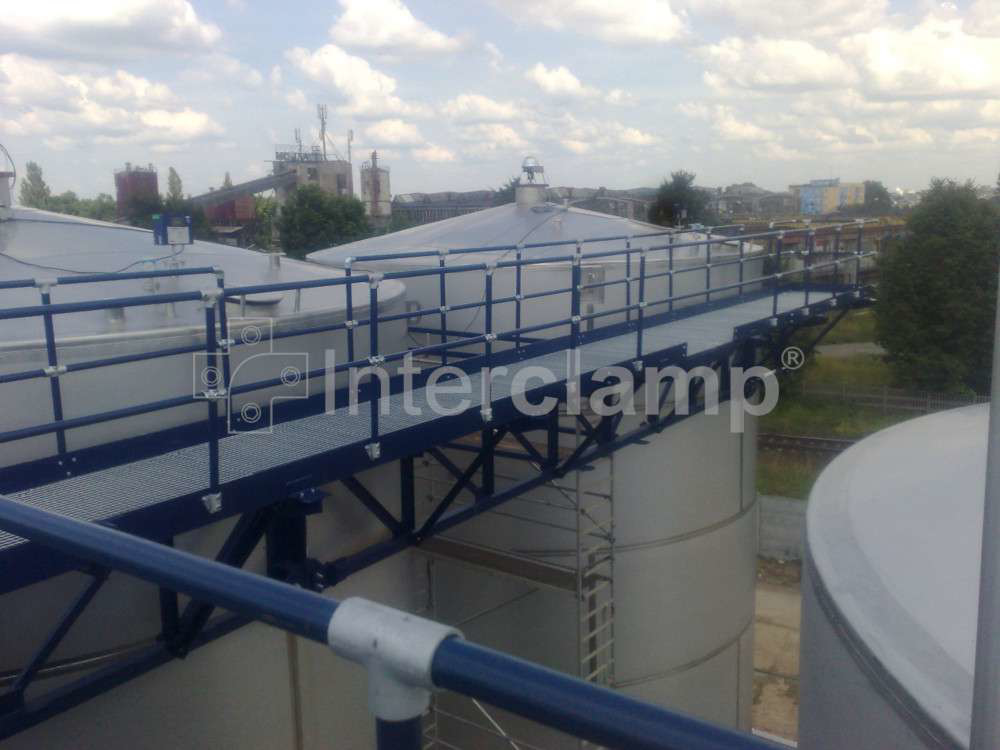 Chemical plant featuring a walkway with a safety guardrail made from Interclamp tube clamp fittings, enhancing safety measures for employees.